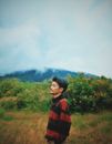 Woman in Red and Black Checkered Long Sleeve Shirt Standing on Green Grass Field