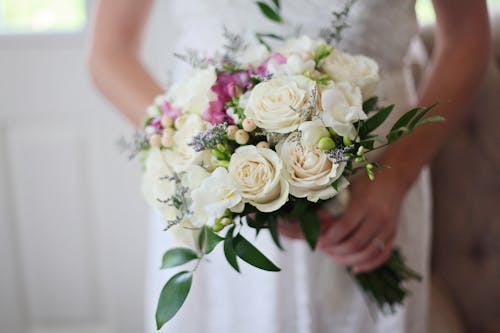 バラの白い花束を保持している花嫁