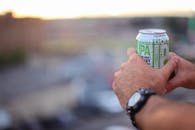 日落时分，一名男子在户外手持啤酒罐，背景模糊