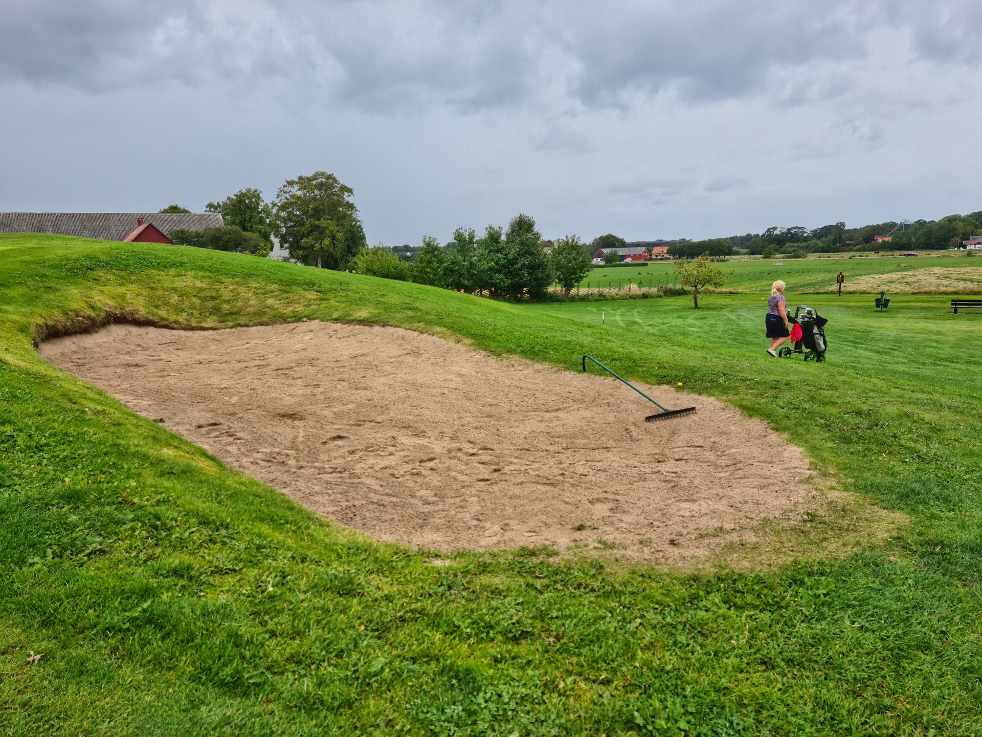 Woman pushing a stroller on a golf course with sand bunker in Båstad, Sweden.