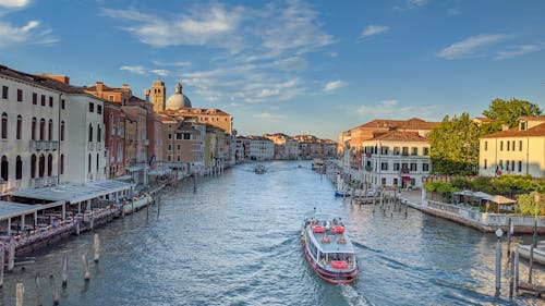 White and Red Boat on Water Near Buildings