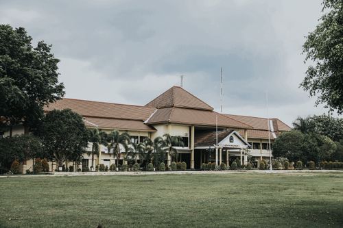 Free Colonial-style building in Yogyakarta, Indonesia, surrounded by lush greenery and palm trees. Stock Photo