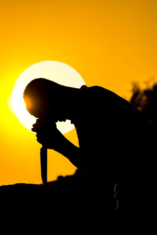 Silhouette of man with knife at sundown