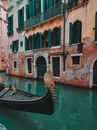 Traditional gondola floating on canal water near aged shabby building with arched windows in Venice