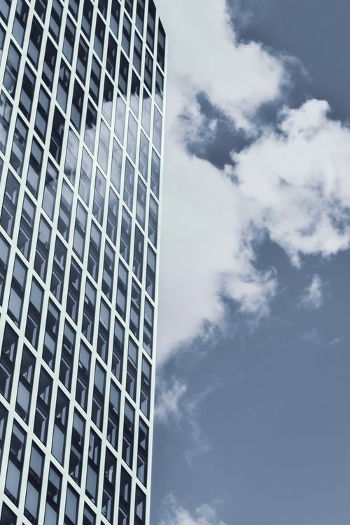 Free From below of modern geometric skyscraper with glass mirrored windows reflecting cloudy blue sky on sunny day Stock Photo