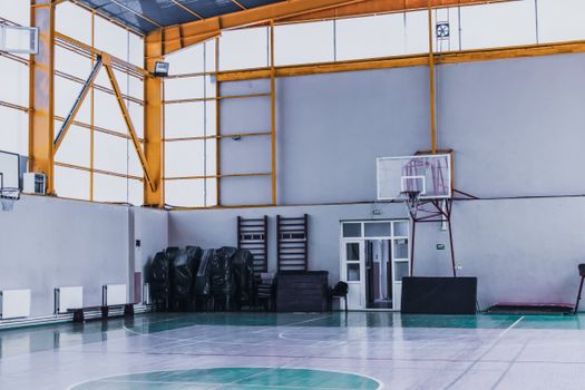 Modern empty sports hall with basketball hoop and various fitness equipment in daytime