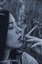 一位年轻女子在大自然的环绕下，于户外吸烟的肖像