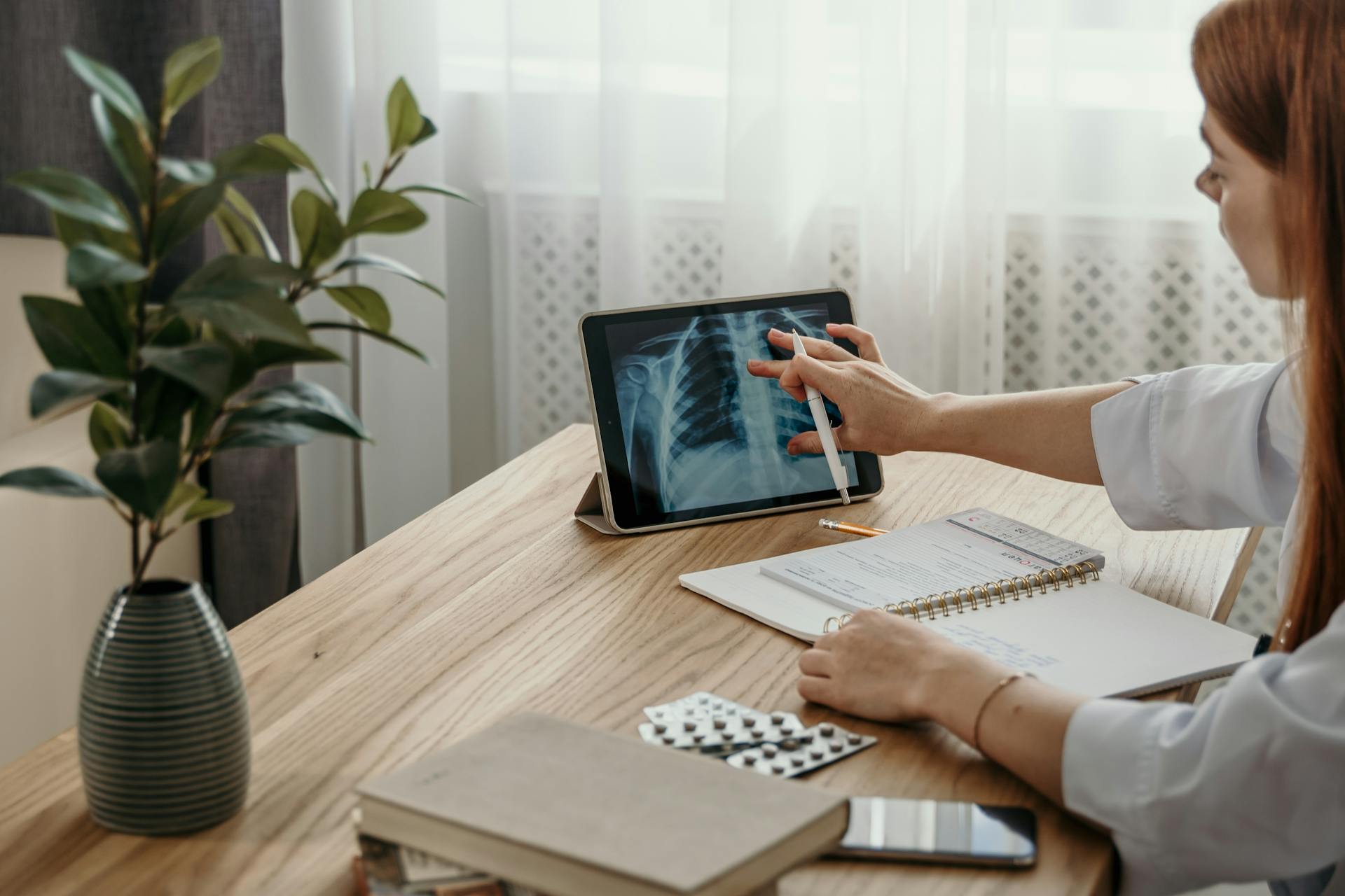 A Woman in White Long Sleeves Looking at the Image on the Tablet