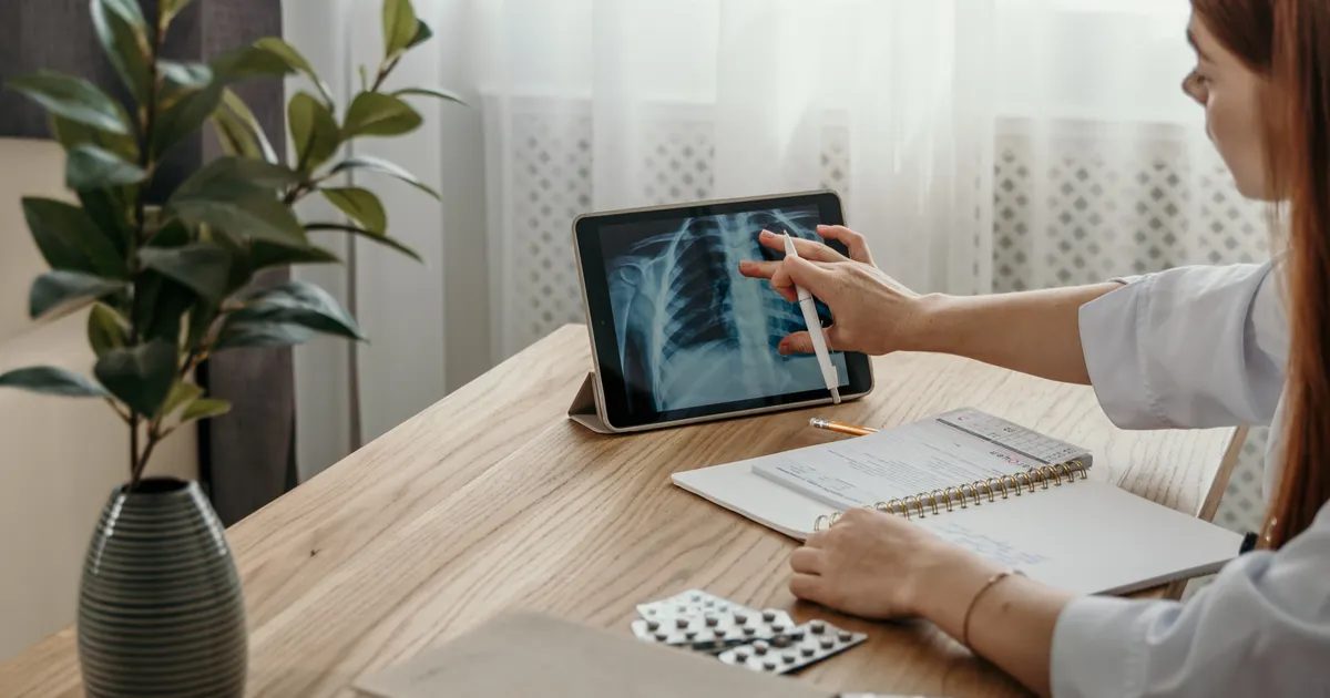 A person pointing at an X-ray on a tablet on a wooden desk, representing clinical AI rules in AB 1979 and SB 503