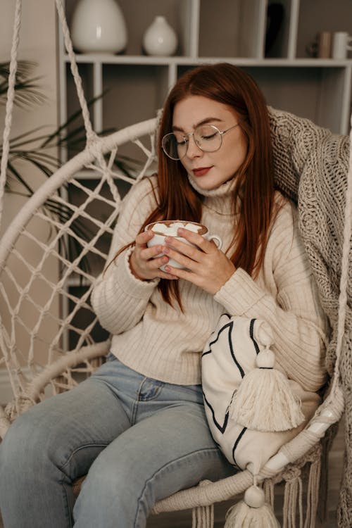 Free Woman Sitting on Egg Chair While Holding a Mug Stock Photo