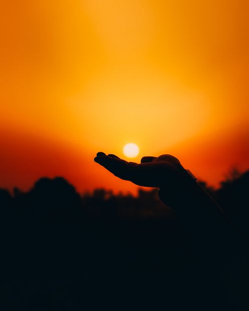 Free Silhouette of a hand holding the sun against a vibrant sunset sky in Butwal, Nepal. Stock Photo