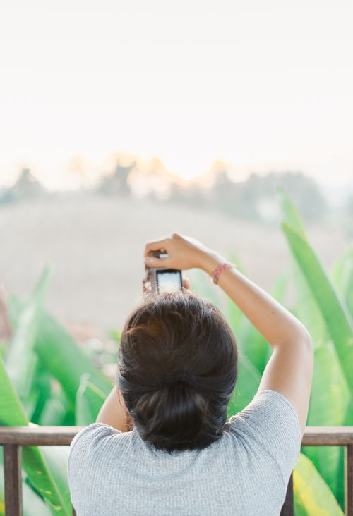 Free Woman taking a photo of a scenic outdoor view with lush greenery. Stock Photo