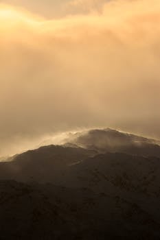 A breathtaking sunrise illuminating snow-covered mountain peaks with soft orange hues.
