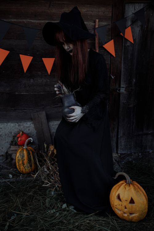 Free A mysterious witch with dark lipstick holds a cauldron in a halloween setting. Stock Photo