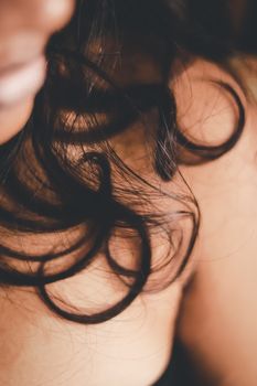 Crop anonymous lady with dark wavy hair wearing black outfit spending time in room