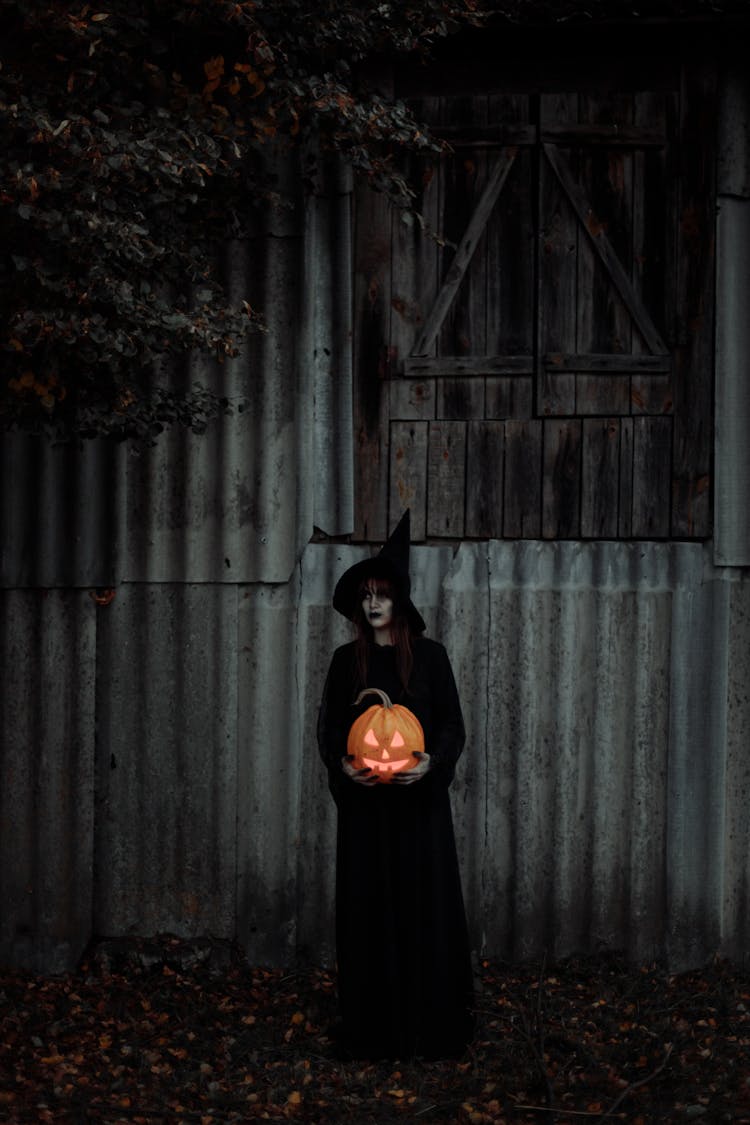 Witch Standing With A Pumpkin In Her Hands