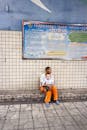A Man Sitting Beside a Tiled Wall with a Baby