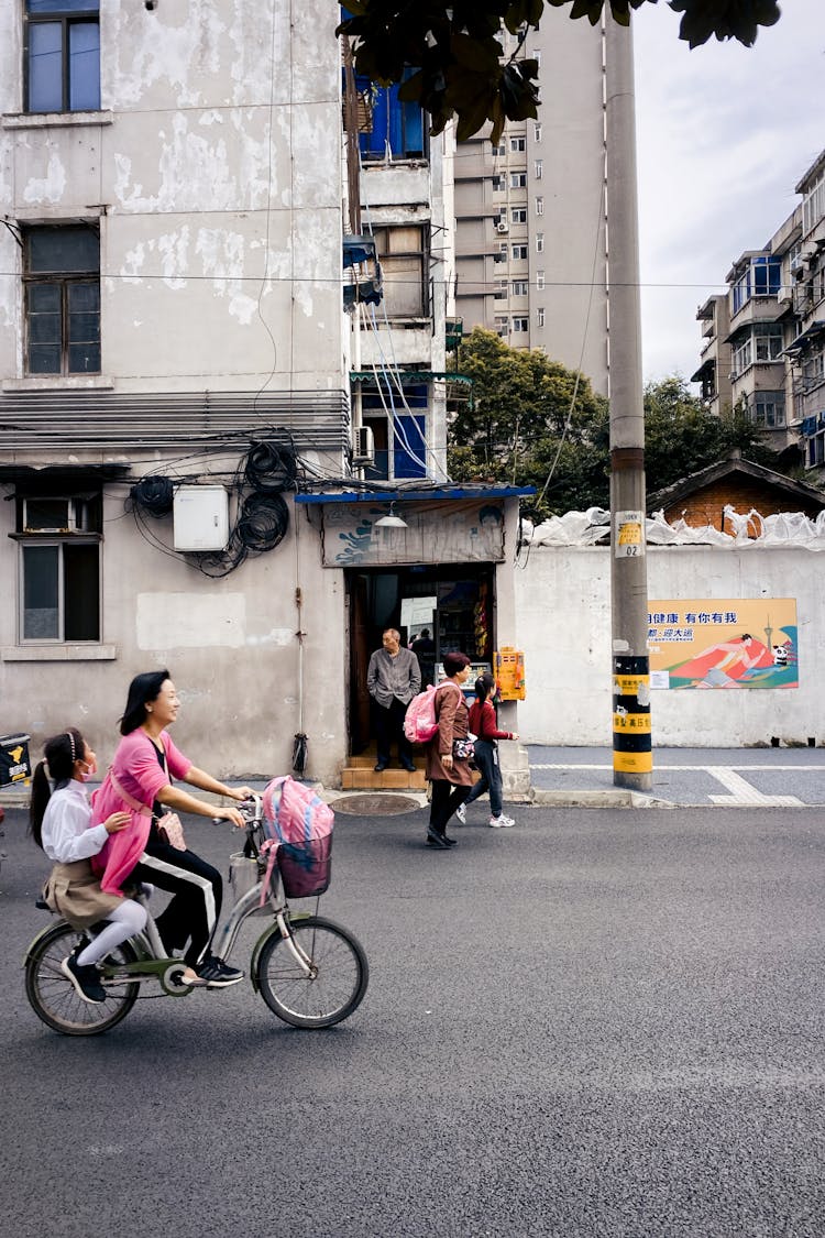 Woman And A Girl Riding A Bike On The Street