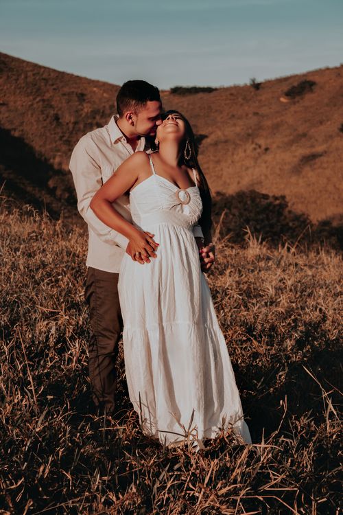 Free A couple sharing an affectionate moment in a sunlit field, capturing the essence of love. Stock Photo
