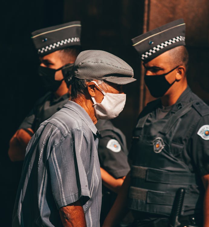 Free Anonymous ethnic policemen and senior male in medical masks on street Stock Photo