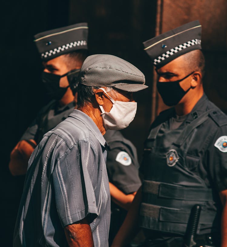 Anonymous Ethnic Policemen And Senior Male In Medical Masks On Street