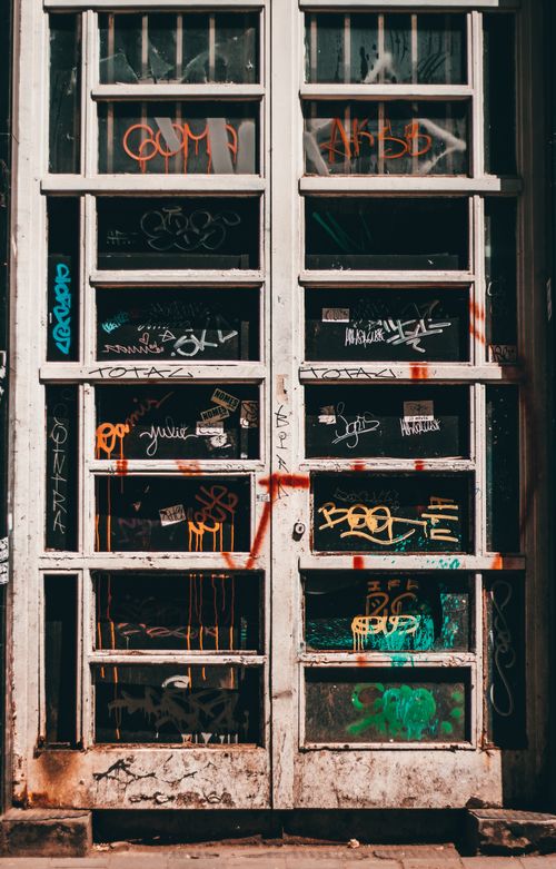 Free Shabby dirty door with graffiti written of aged building located on street on sunny day Stock Photo