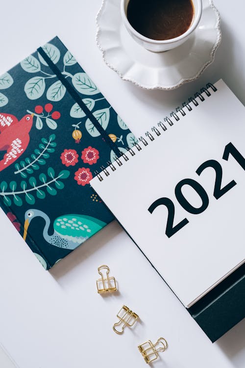 A 2021 Desk Calendar on a Planner Beside Paper Clips