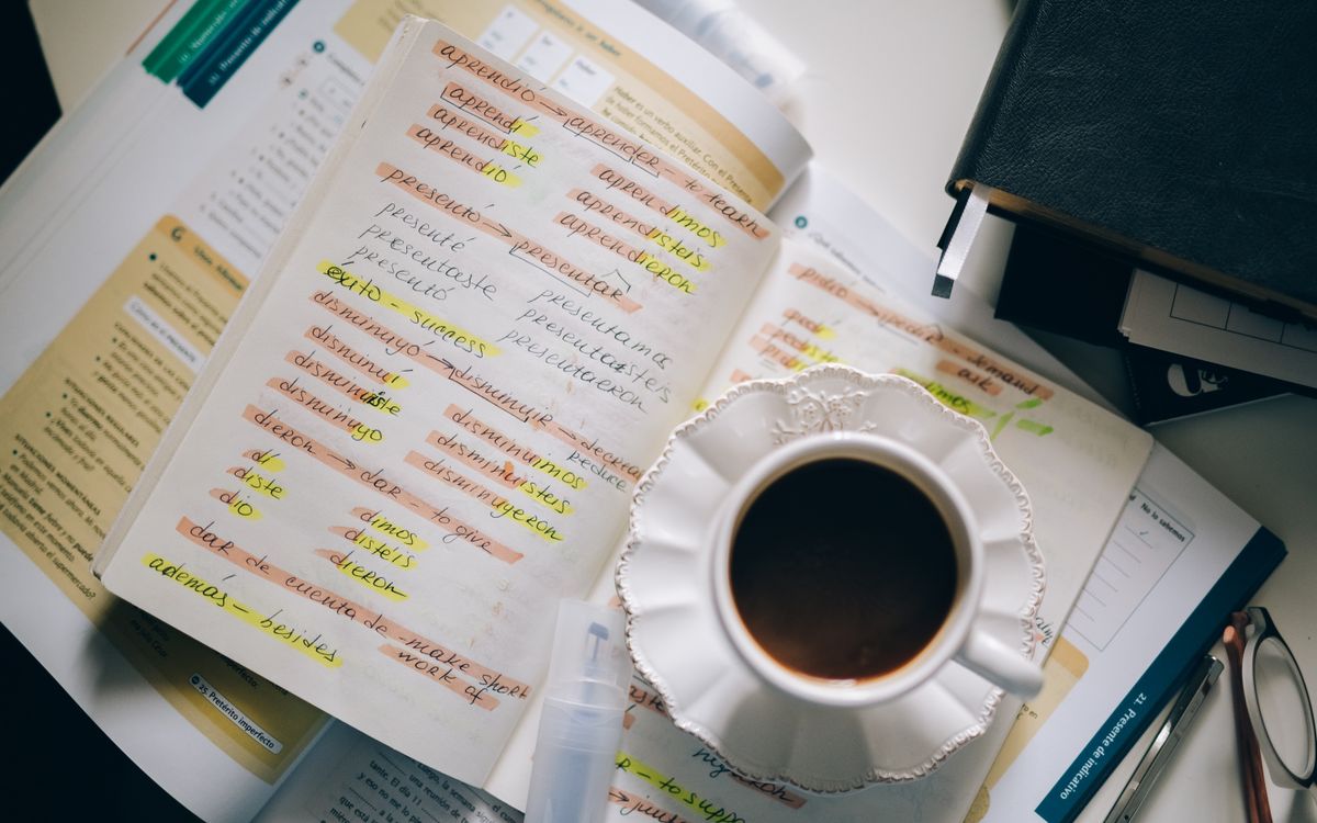 A cup of coffee on handwritten Spanish notes for language learning inspiration.