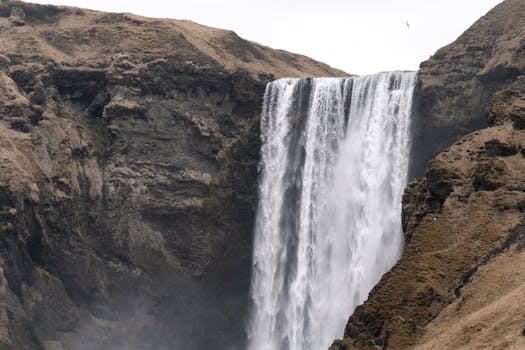 Majestic view of Skógafoss waterfall cascading down a cliffside in Iceland, capturing nature's raw beauty.