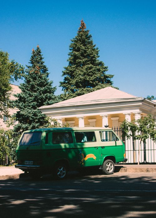 Free Green Volkswagen van parked outside a classic building on a sunny day in Николаев, Ukraine. Stock Photo