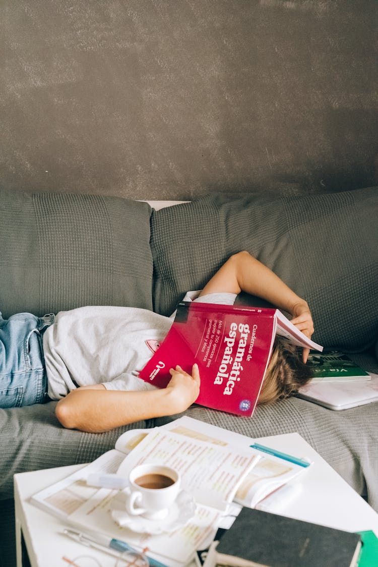 A Person With A Book On The Face Lying Down The Couch