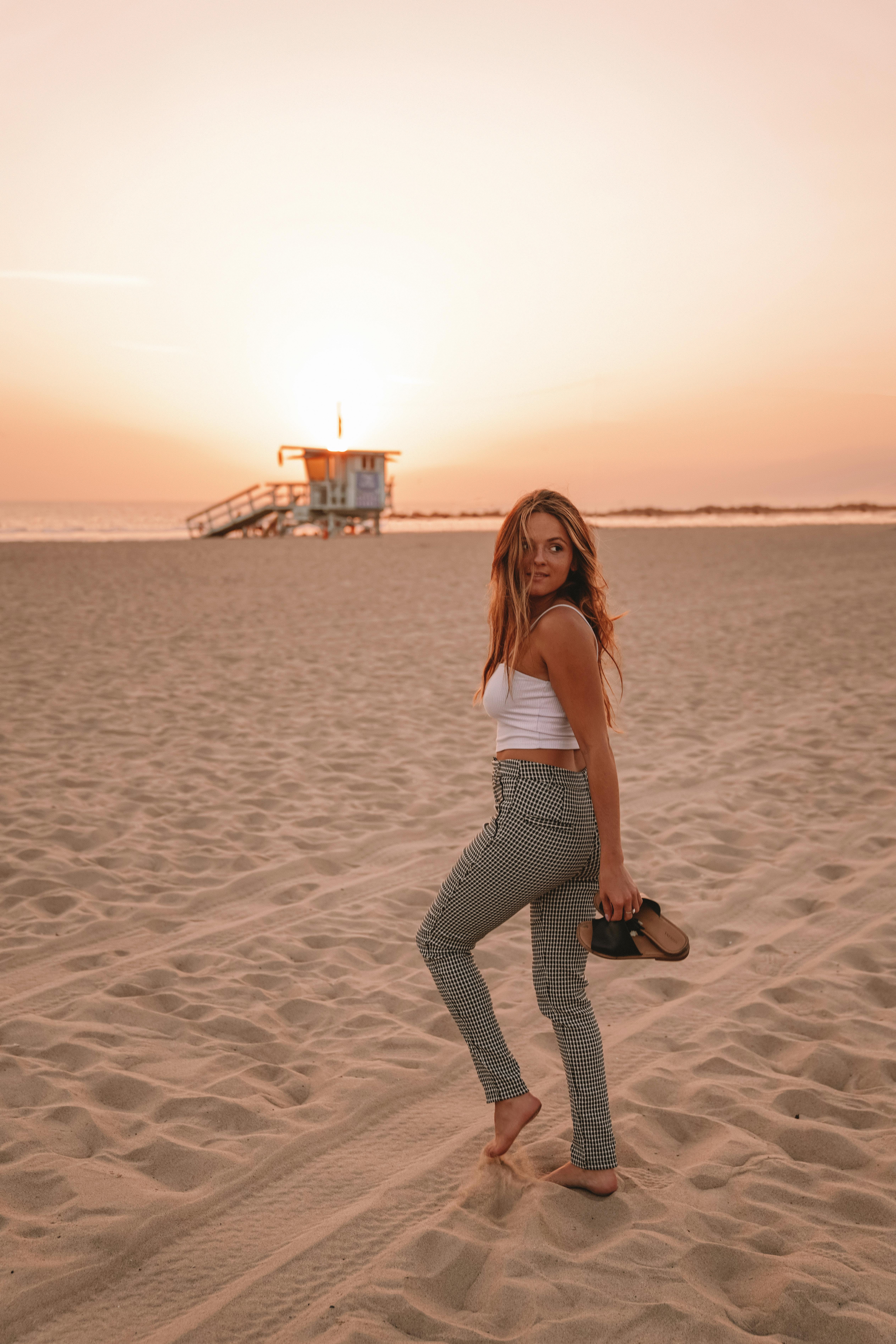 woman strolling on beach at sunset