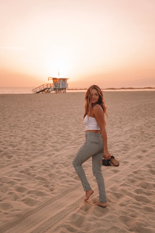 Woman strolling on beach at sunset