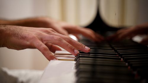 Free Focused view of hands playing piano keys indoors with reflection visible. Stock Photo