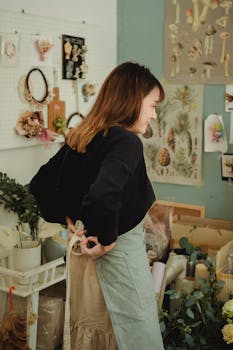 A female florist tying her apron in a cozy floral shop, ready to start her day.