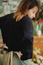 Ethnic florist tying bow on apron while preparing for work