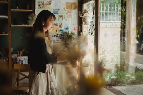 Side view of Asian woman  preparing cozy floral workshop for working day