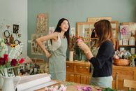 Laughing young female florist preparing for work on workshop