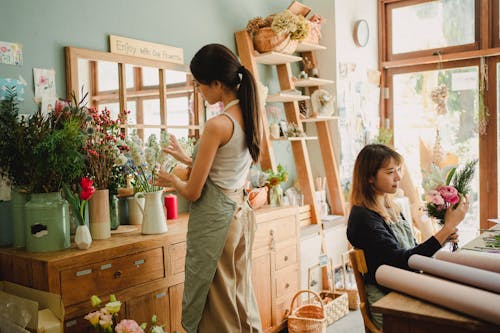 Concentrated diverse women making flower compositions in floral market