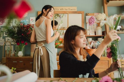 Free Focused multiethnic women in aprons working in cozy floral shop with various fresh flowers Stock Photo