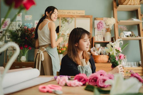 Серьезный азиатский флорист делает букет во время работы с коллегой