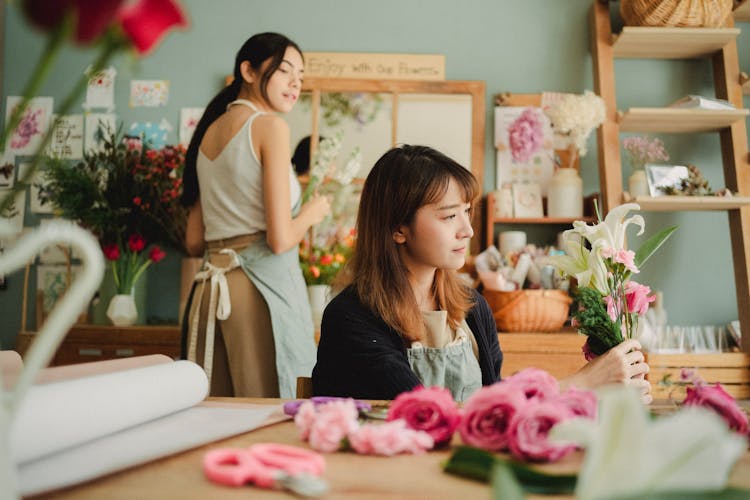 Serious Asian Florist Making Bouquet During Work With Colleague