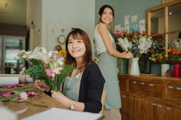 Happy Asian Florist Making Bouquet With Assistant