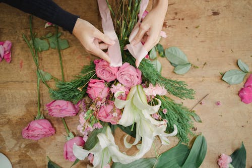 Florist tying ribbon on bouquet of flowers