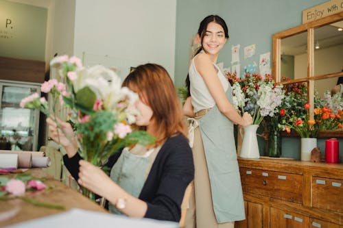 Cheerful florist preparing floral decoration in vase in workshop