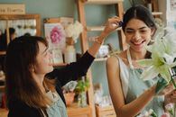 在室内时尚的花店里，穿着围裙微笑的多种族花店员工正在交流