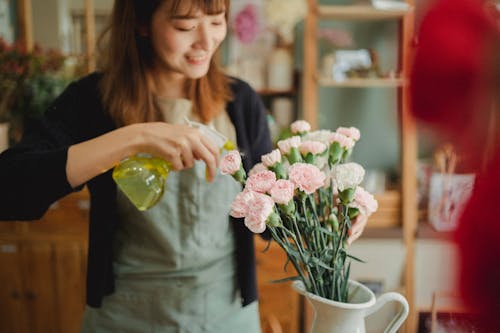 Asian woman spraying flowers in shop