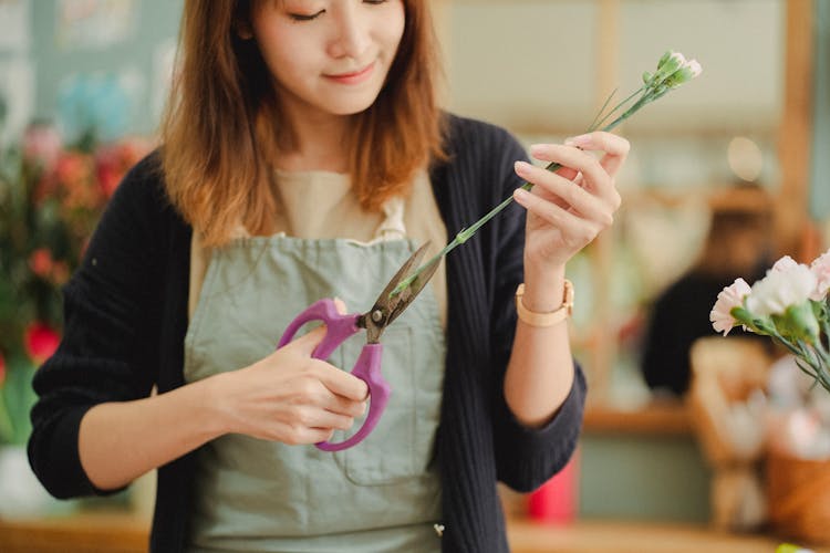 Crop Asian Woman Cutting Flowers In Shop