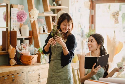 两名女士在一家舒适的花店里，周围都是鲜花，享受着工作