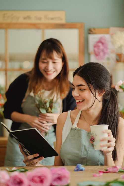 Free Happy florists colleagues smiling and reading notes during work day in flower shop Stock Photo